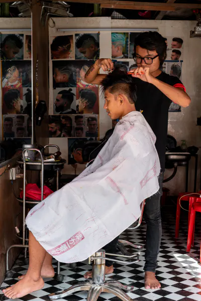 Bespectacled barber cutting hair