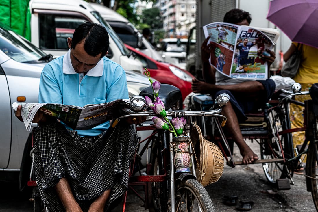 Pedicab drivers reading tabloid newspaper