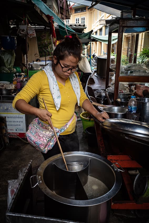 Woman boiling noodles in Tha Tien Market
