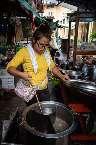 Woman boiling noodles in Tha Tien Market