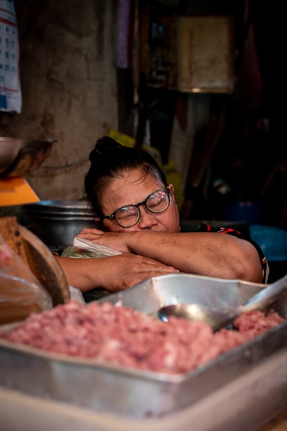 Female butcher taking a nap in Khlong Toei Market