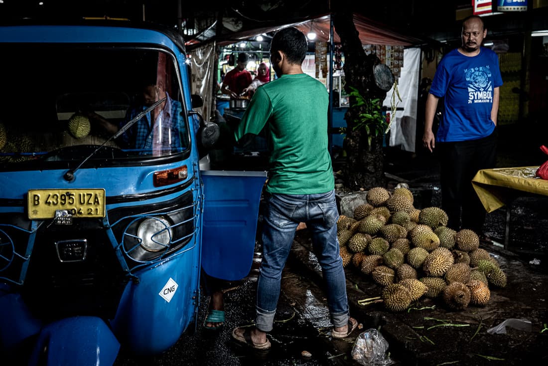 Men loading durians onto Bajaj