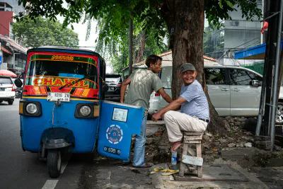 大きな街路樹の横に停まっていたバジャイと呼ばれる三輪タクシー