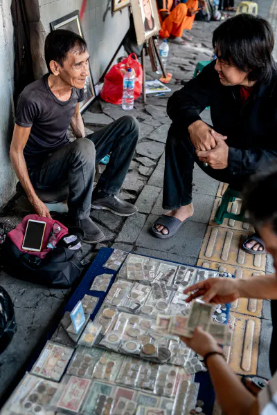 Old coin seller doing business in a street corner in Jakarta