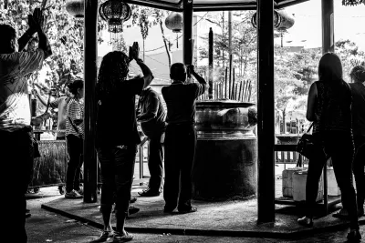 Silhouetted people praying around the incense burner in Jin De Yuan