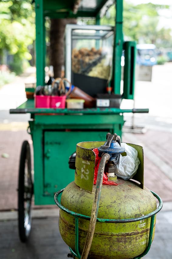 Green gas cylinder next to a food stall