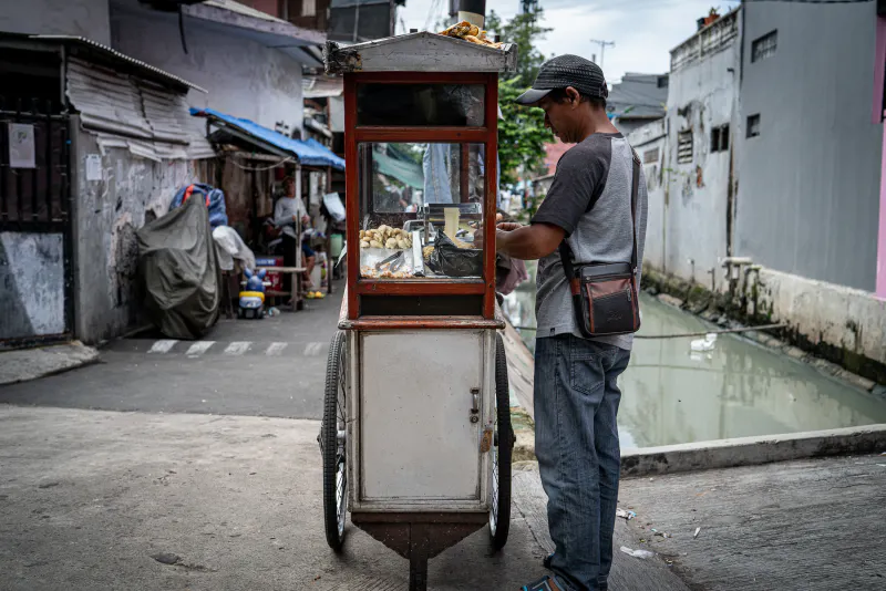 Mobile food stall by the small river in the residential area of Jakarta