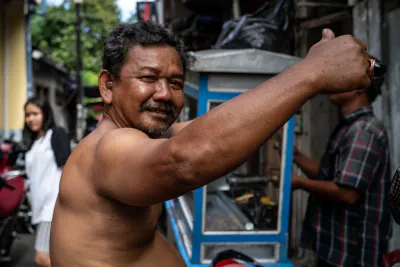 Shirtless man raising his arm up in front of a food stall
