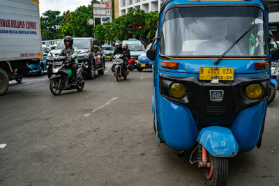 Bajaj parked on the side of a busy road