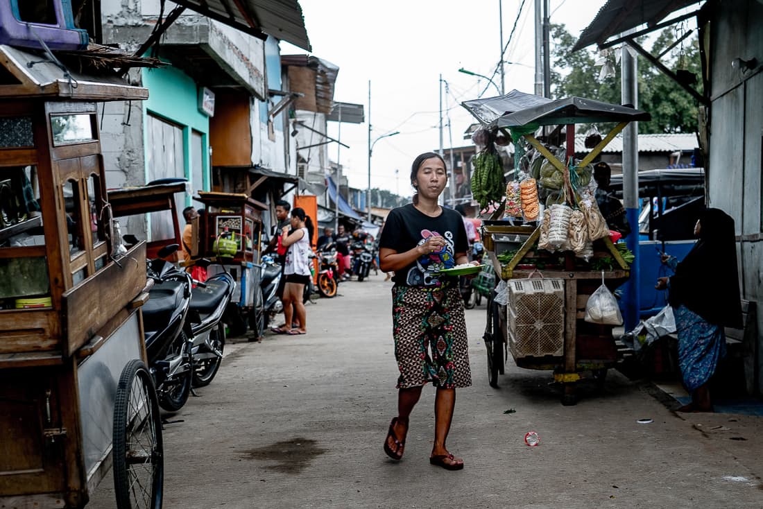 Woman walking down an alley with a plate in her hand