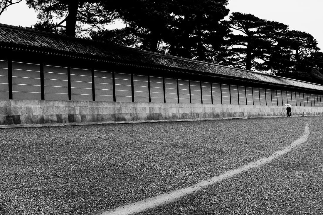 Person with an umbrella walking along the wall of the Kyoto Imperial Palace