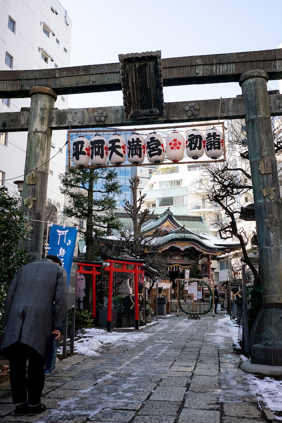 Man bowing at the torii of Hirakawa Tenmangu Shrine