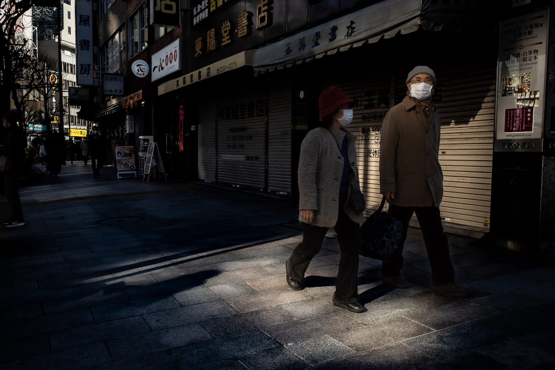 Old couple walking side by side wearing masks