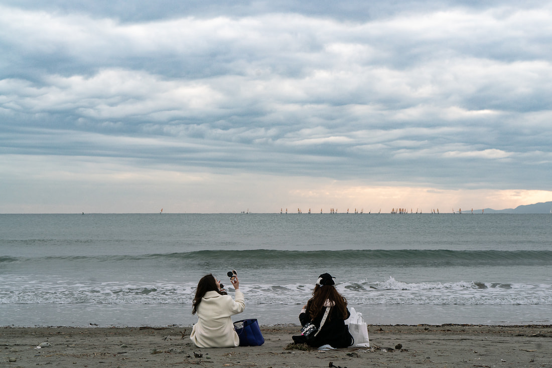 海を向いて座るふたりの女性