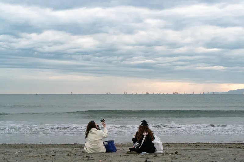 Two women sitting facing the sea