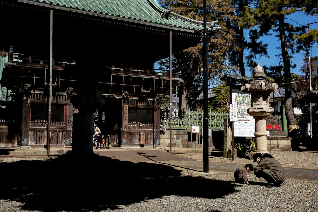 Parent and child crouching in front of the gate of Myohoji Temple