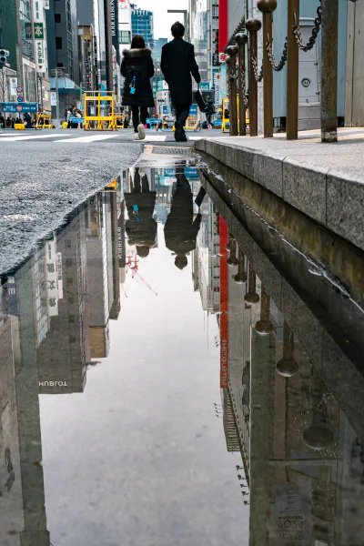 Couple reflected in a puddle of water in Ginza