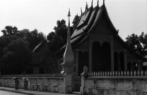 Buddhist monks walking beside a temple with umbrella