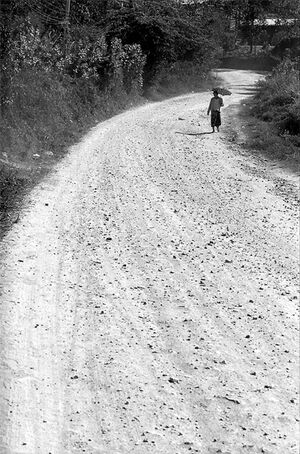 Woman walking dirt road with sunshade