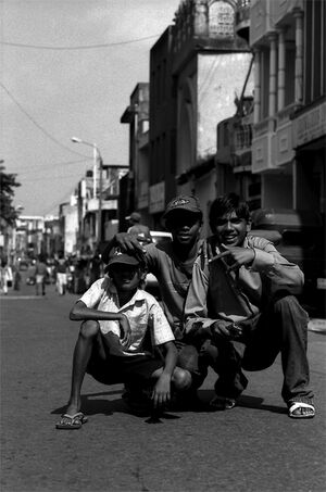 Three boys crouching down in the center of street