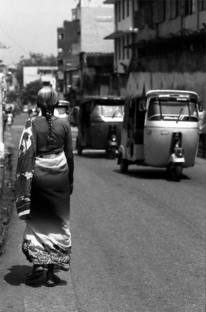 Three wheelers passing by woman with saree