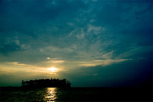 沖合の島の向こうに沈んでいく太陽