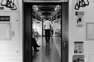 電車の中でうなだれながら歩く男