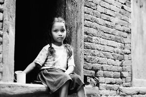 Girl sitting at entrance of house