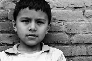 Boy standing against brick wall