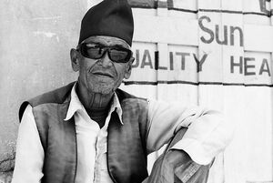 Old man wearing sunglasses and Bhadgaunle Topi