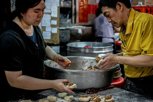 Man and woman making meat buns one after another