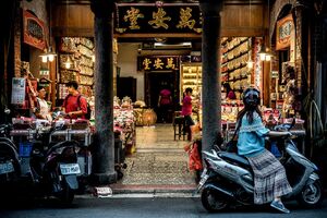 Young woman on motorbike stopping in storefront
