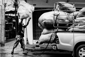 Man tossing big bag onto car