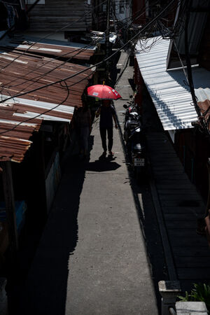 トタン屋根の間を進んでいた赤い傘を差した人影