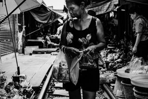 Woman walking on railroad track in Maeklong Railway Market