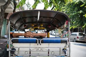 Man resting in the back seat of a tuk-tuk