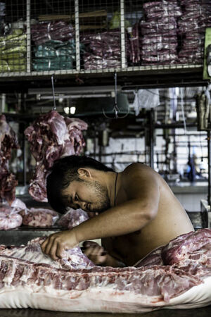 Young butcher cutting pork
