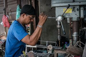 工作機械のドリルで穴を開ける男
