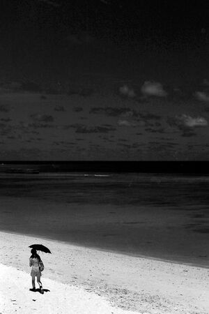 Woman walking beach with black sunshade