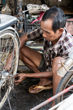 自転車タクシーを修理する男