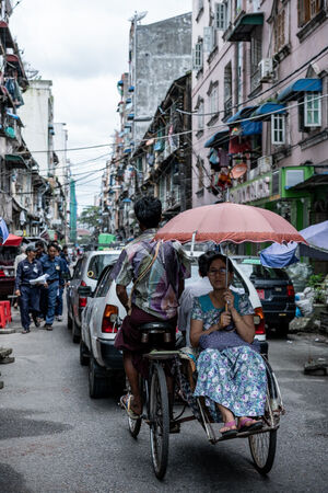 自転車タクシーの上で傘を差す女性