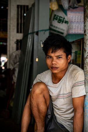 Young man sitting at entrance of market