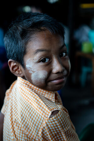 Boy with Thanaka on his face looking back
