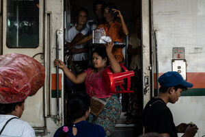 Vendor coming out of train car with tray on head