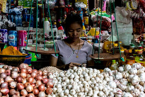 Woman working on the other side of pile of garlic