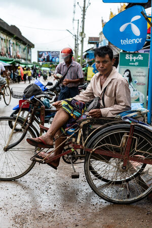 市場の前で客待ちする自転車タクシーの車夫