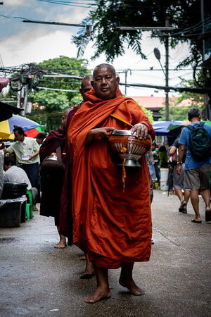 托鉢の鉢を抱えて歩く僧侶たち