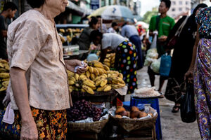 Older woman walking in front of fruits