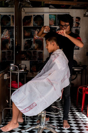 Bespectacled barber cutting hair