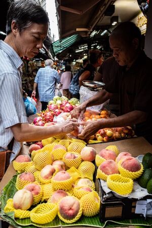 Man buying peach in a fruit shop